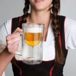 Woman holding beer in a wine glass within a glass beer tanker